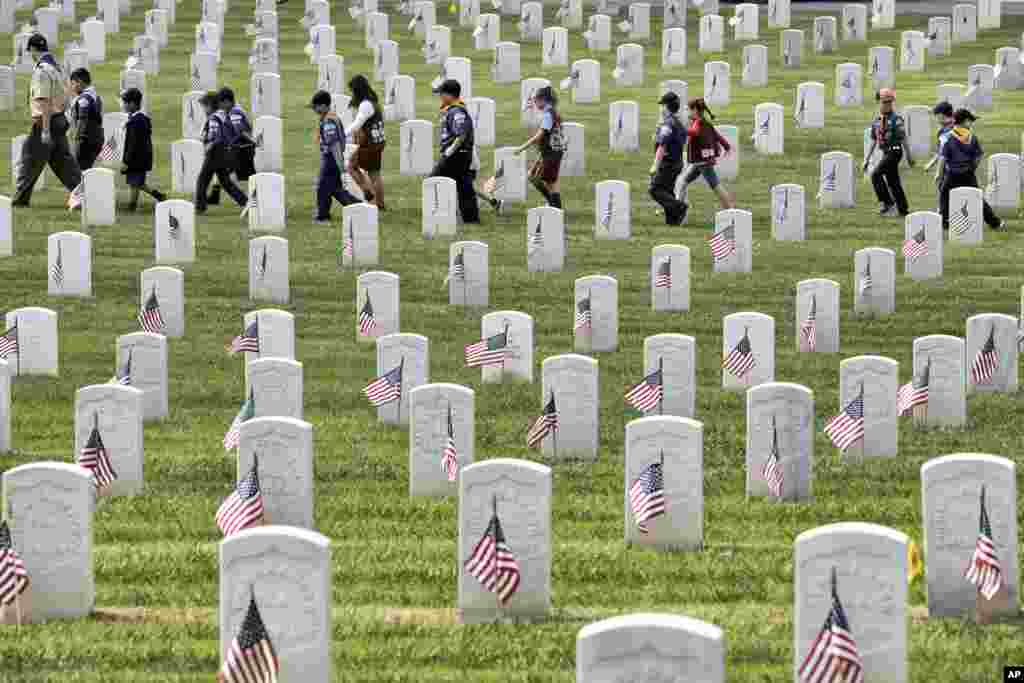 Boy Scouts and Girl Scouts walk between grave stones after helping place flags at the Los Angeles National Cemetery, May 26, 2018.