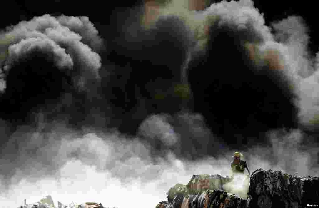 A firefighter extinguishes a blaze as it burns through a pile of old tires at a recycling center in Ciudad Juarez, Mexico, May 2, 2018.