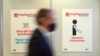 FILE - A person walks past pictograms in the vaccination center at the football stadium in Duesseldorf, western Germany, Dec. 1, 2020. 