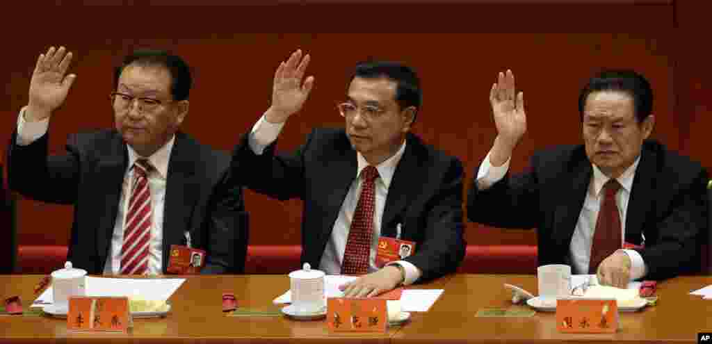 2012年11月4日,中国副总理李克强(中)、宣传大总管李长春(左)和政法委大总管周永康在北京召开的中共18大会议上举手。