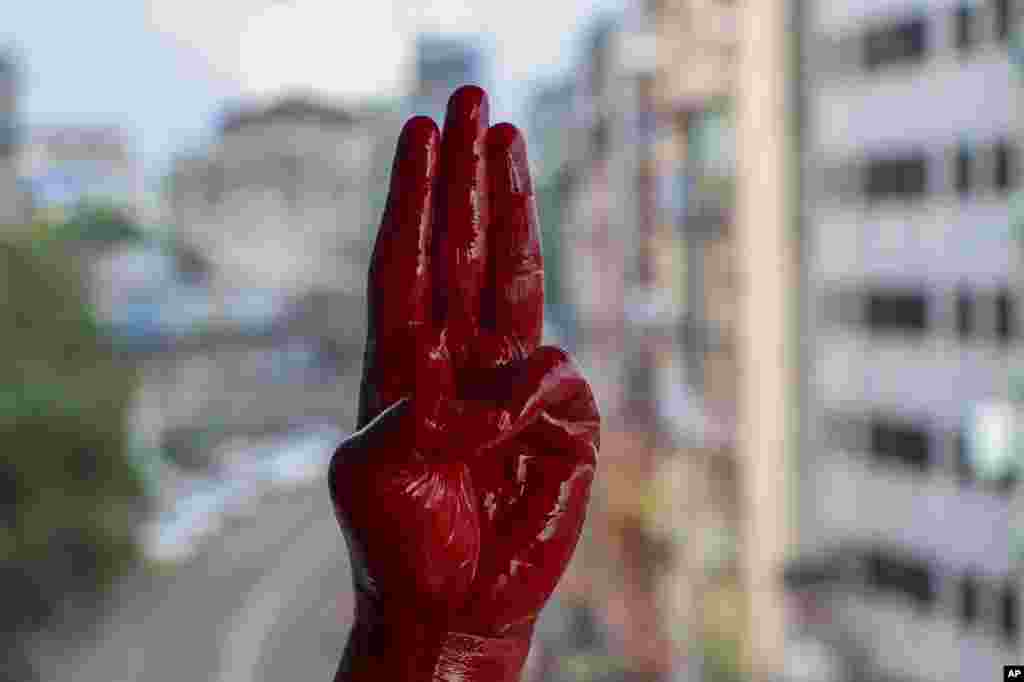 An anti-coup protester shows the three-fingered salute of resistance on his red painted hand in memory of protesters who lost their lives, in Yangon, Myanmar.