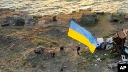 乌克兰国防部2022年7月7日公布的照片显示，乌克兰士兵在黑海的蛇岛上升起一面国旗。蛇岛不久前曾被俄军占领。（照片来自美联社）
