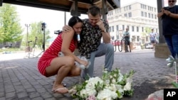 新婚夫妇布鲁克与马特·斯特劳斯在伊利诺伊州芝加哥近郊海兰帕克的枪击惨案现场附近留下两人婚礼上的鲜花并为死难者默哀。(2022年7月5日)