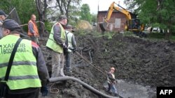 Працівники комунальних служб працюють біля вирви у дворі лікарні в Харкові після російського масованого ракетного удару по Україні, що пошкодив чотири електростанції. 27 квітня 2024 року.