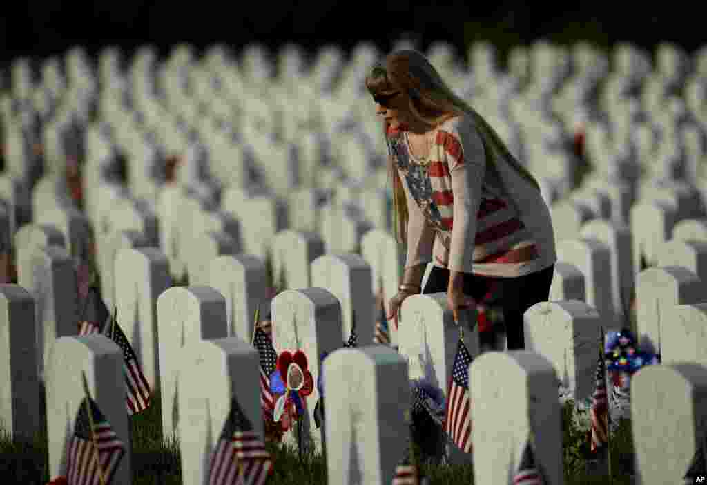 Patrica Kelly pauses at her father's grave at Levenworth National Cemetery on the eve of Memorial Day, May 27, 2018, in Leavenworth, Kansas.