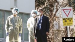 日本卫生官员戴着防疫口罩在东京的国立国际医疗研究中心等候从武汉撤回国的日本侨民。（2020年1月30日）