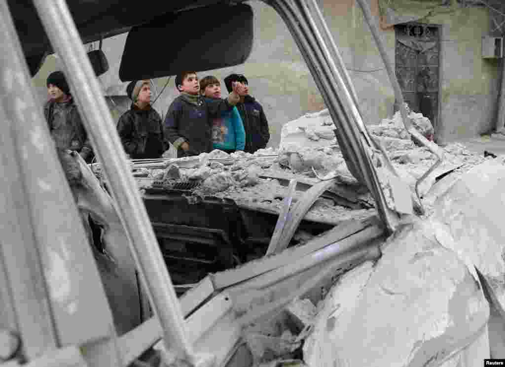 Boys stands near a damaged site after an airstrike on the Eastern Ghouta town of Misraba, Syria.
