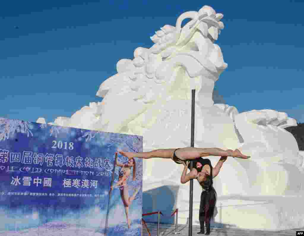 2018年12月20日,在中国黑龙江省东北部漠河的零下23摄氏度的严寒下,在龙形雪雕前面举行钢管舞比赛,一位舞者参赛。漠河在中国领土的最北端。