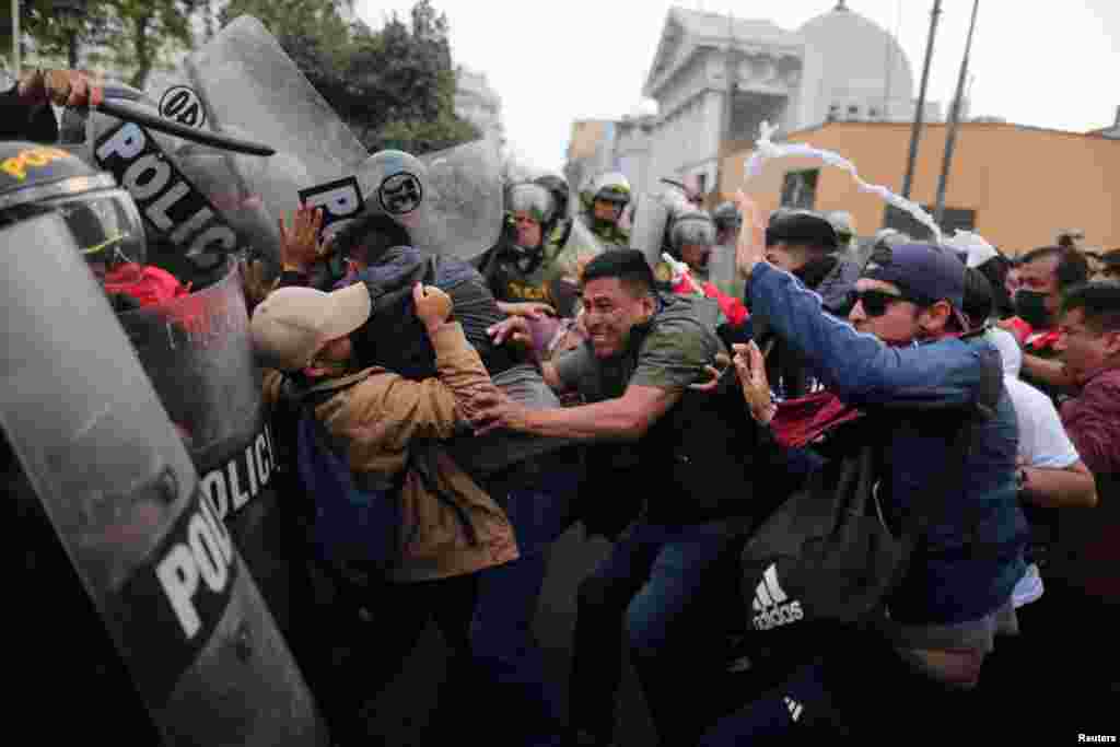 Demonstrators clash with riot police during a protest demanding presidential elections and the closure of Congress after ousted Peruvian leader Pedro Castillo was detained in a police prison following his removal from office, in Lima, Dec. 8, 2022. 