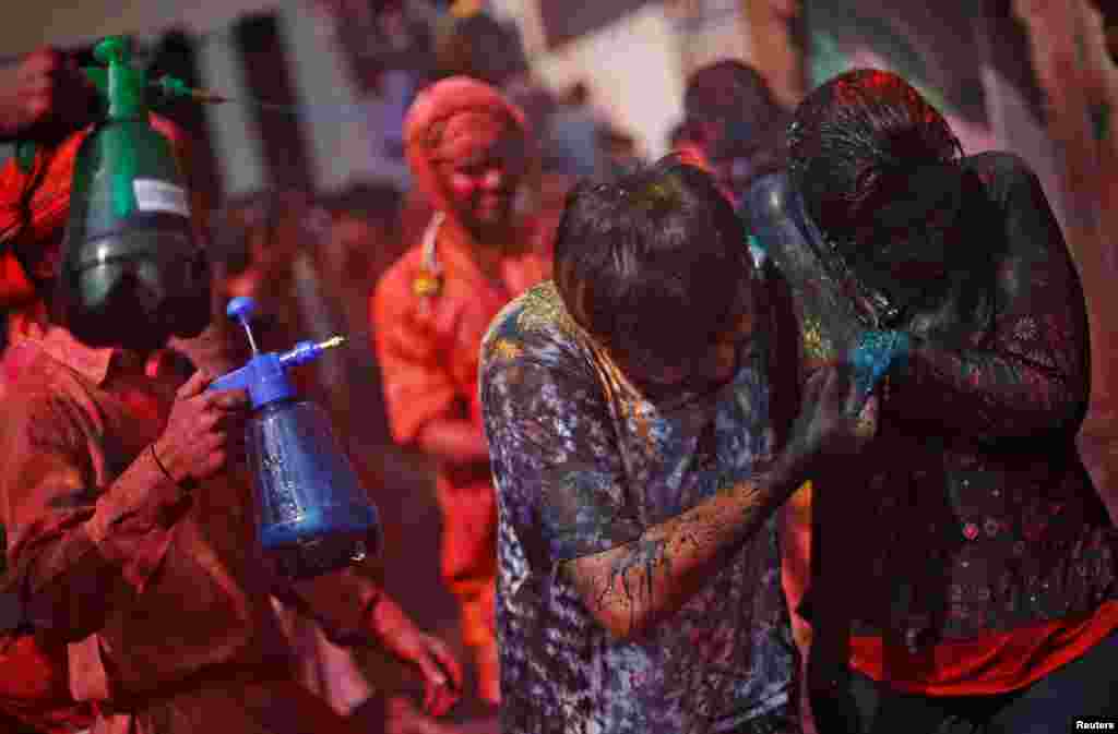 A couple run for cover as boys spray colored water on them during religious festival of Holi inside a temple in Nandgaon village, in the state of Uttar Pradesh, India.