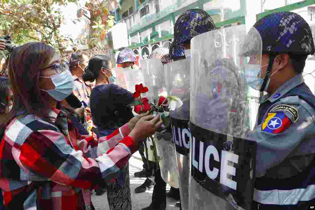 Supporters give roses to police while four arrested activists make a court appearance in Mandalay, Myanmar. Hundreds of students and teachers have taken to Myanmar's streets to demand the military hand power back to elected politicians.