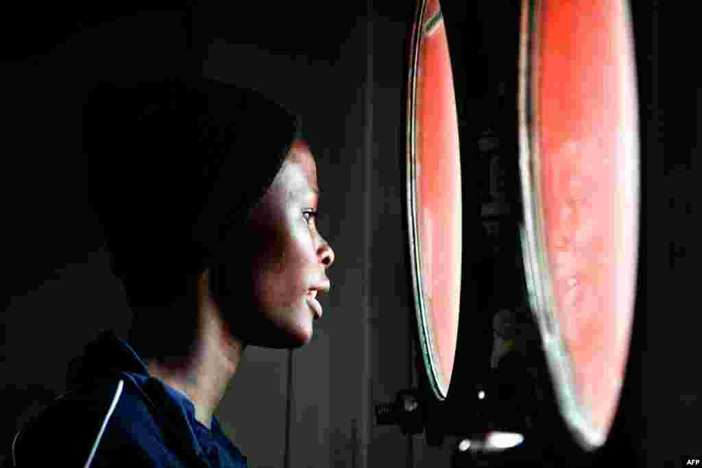 A woman peers out from the porthole of the MV Aquarius upon its arrival at the Sicilian port of Messina, Italy.