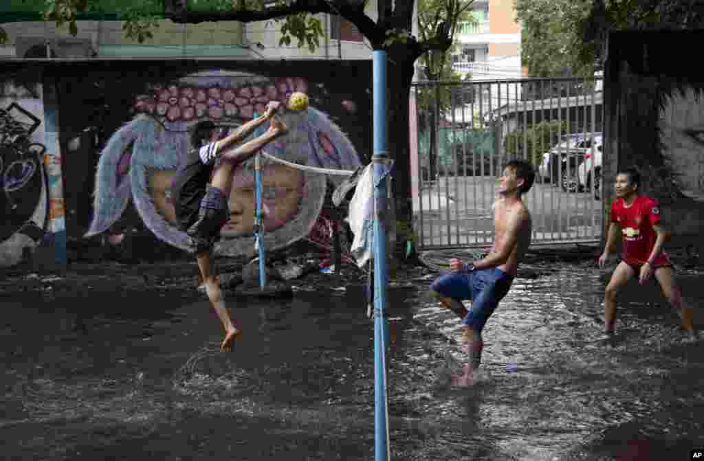 A migrant worker kicks a rattan ball during a game of Chinlone in a field flooded by rain water in Bangkok, Thailand.