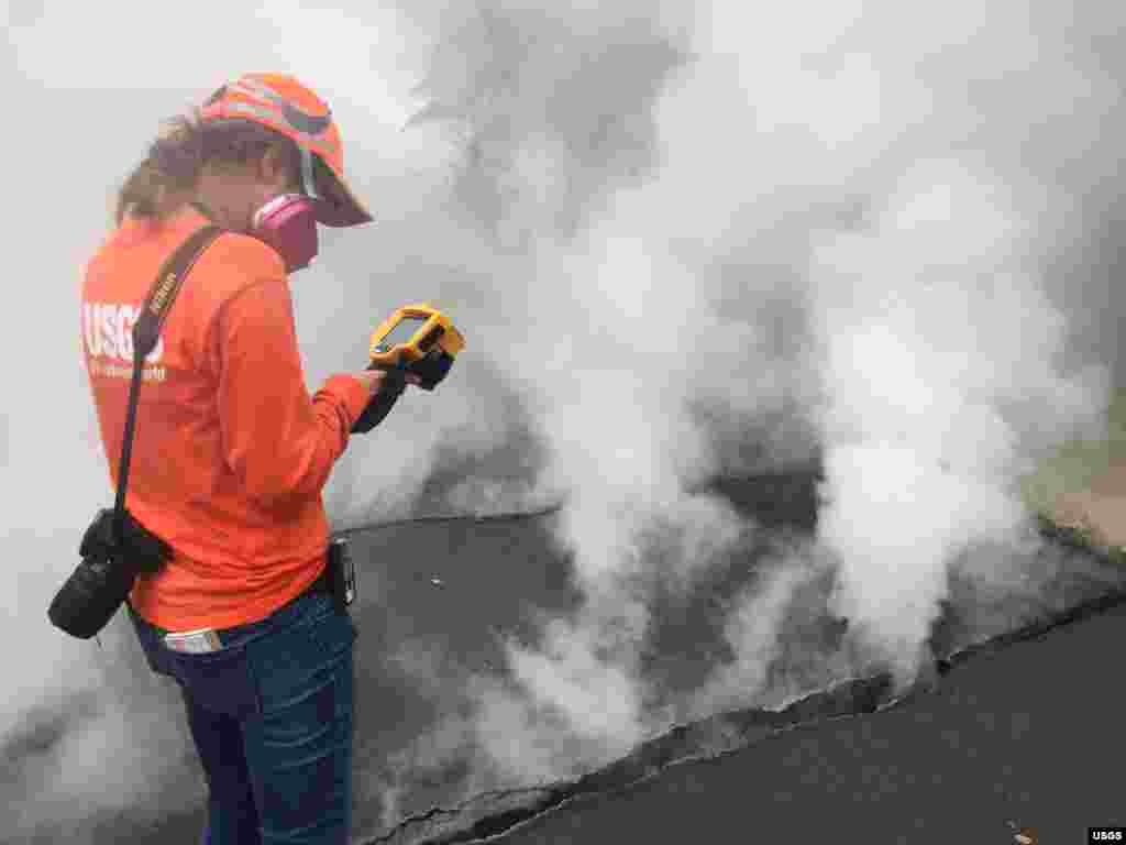 HVO geologist measures a temperature of 103° C (218° F) at a crack along Nohea Street, Leilani Estates, Hawaii, My 9, 2018. The asphalt road was describes as "mushy" from the heat.