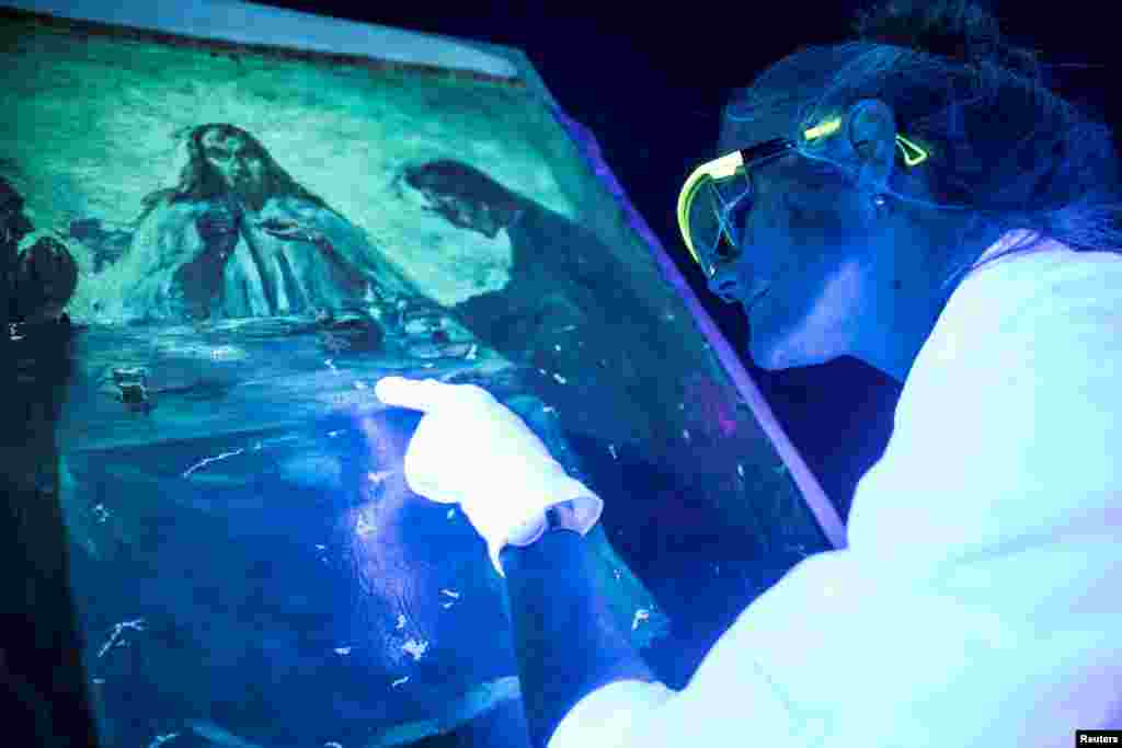 Conservation technician Mikala Bagge looks at Emil Nolde’s painting "Dinner in Emmaus" in UV light to evaluate the damages after it has been stolen in 2014 and submerged in Jan. 2018, in Brede, Denmark.