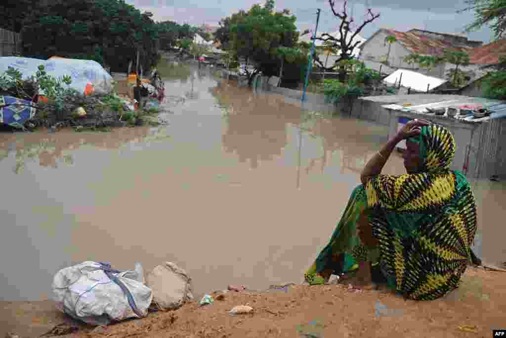 A woman living at a camp for the internally displaced sits on high ground above a flooded street in Mogadishu, after temporary shelters were inundated in Somalia's capital following heavy overnight rainfall.