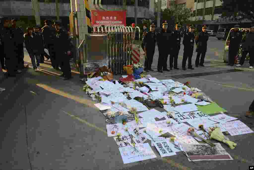 安全警卫人员2013年1月7日站在那些安放在南方周末总部外面的标语和鲜花旁边