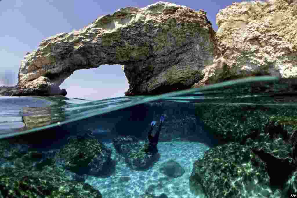 Cypriot marine ecologist Louis Hadjioannou dives to photograph the coral as he monitors the impact of climate change in the crystal clear waters of Glyko Nero in Ayia Napa, off the island's southeastern shore, Cyprus.