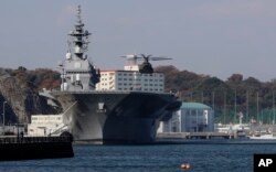 在日本横须贺，一架直升机准备降落在日本海上自卫队“出云”号直升机驱逐舰的飞行甲板上。（2016年12月6日）