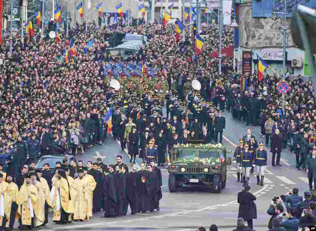 People watch as the coffin of late Romanian King Michael is driven to the patriarchal cathedral, in Bucharest, Romania, Dec. 16, 2017. Tens of thousands of Romanians have joined European royals to pay their respects to late King Michael who is being given a state funeral in the capital.