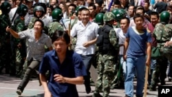 资料照：手持棍棒的汉族人冲破武警人墙，试图攻击维族地段。(2009年7月7日)
