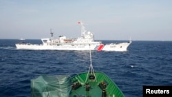 2014年5月14日, 在越南海岸外大约210公里海域，从越南巡逻船上看到的中国海警船。越南船只靠近中国在有争议水域部署的一座石油钻井平台时，会遭到中国船只抵近拦阻。
