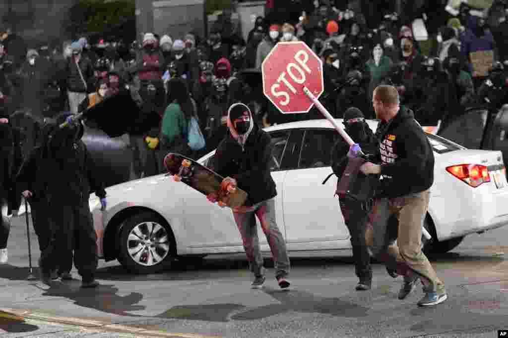 Protesters chase a street preacher, right, who was using a loudspeaker to deliver a sermon during a protest against police brutality, Jan. 24, 2021, in downtown Tacoma, south of Seattle, Washington.