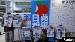 香港苹果日报员工手持最后一起报刊在公司标志旁留影。（2021年6月24日）