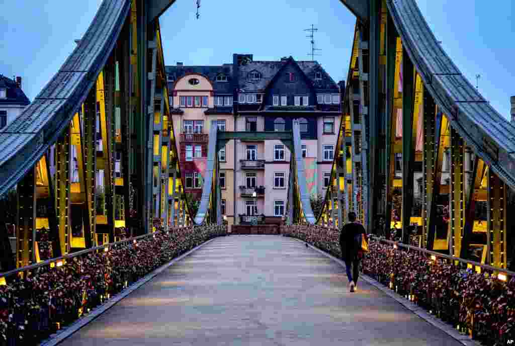 A woman walks over the "Eiserner Steg" (iron footbridge) decorated with love locks in downtown Frankfurt, Germany, Sept. 7, 2021.