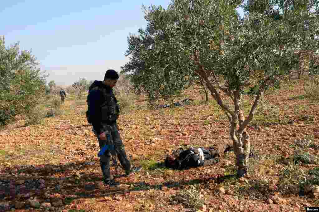 Lực lượng trung thành với Tổng thống Syria Bashar al-Assad đứng cạnh thi thể của các thành viên quân đội Giải phóng Syria tại Tal Hassil, ngày 31/12/2012.