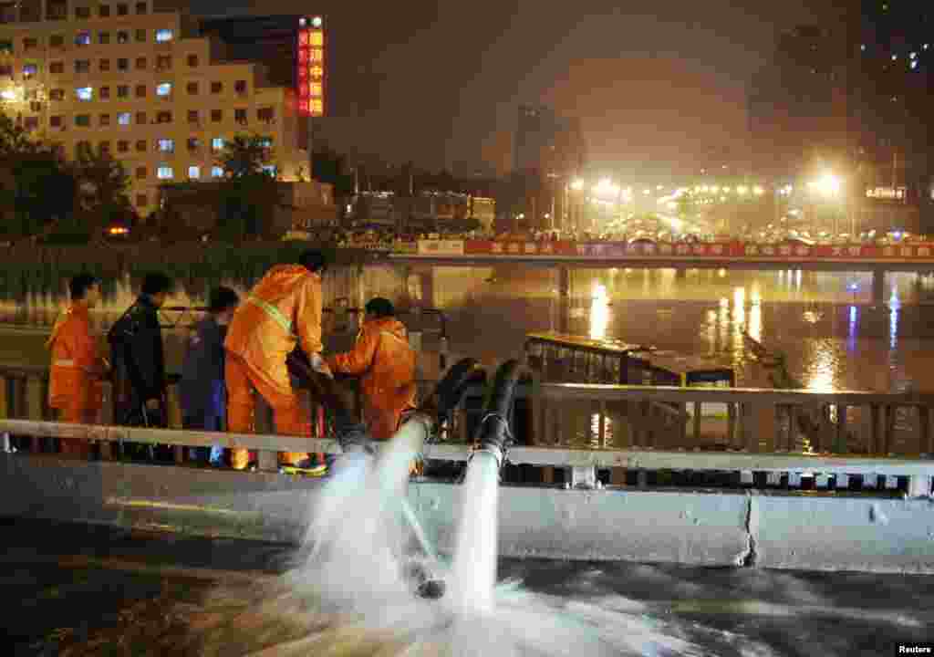 Công nhân bơm nước lụt gần một chiếc xe lớn bị mắc kẹt do mưa lũ tại Bắc Kinh, 21/7/2012.