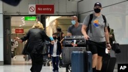 A woman runs to greet a child as passengers arrive at Terminal 5 of Heathrow Airport in London, Aug. 2, 2021, as travelers fully vaccinated from the United States and much of Europe were able to enter Britain without quarantining.