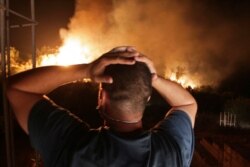 FILE - A man looks at a forest fire near the village of Larbaa Nath Irathen, near Tizi Ouzou, in the mountainous Kabyle region, 100 kilometers east of Algiers, Aug.11, 2021.