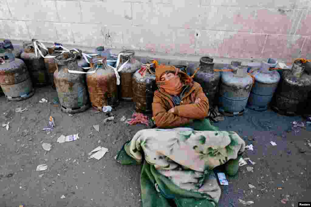 A man sleeps next to a queue of cooking gas cylinders outside a gas filling station amid a scarcity in cooking gas supplies in Sana'a, Yemen.