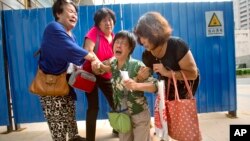 鲍兰芳（音 右二）与其他马航MH370航班的乘客亲属在马航驻北京办公室外抗议，她的儿子、女婿和孙女都是马航370航班的乘客，她在与记者交谈时悲痛得难以自制。（2015年8月6日）