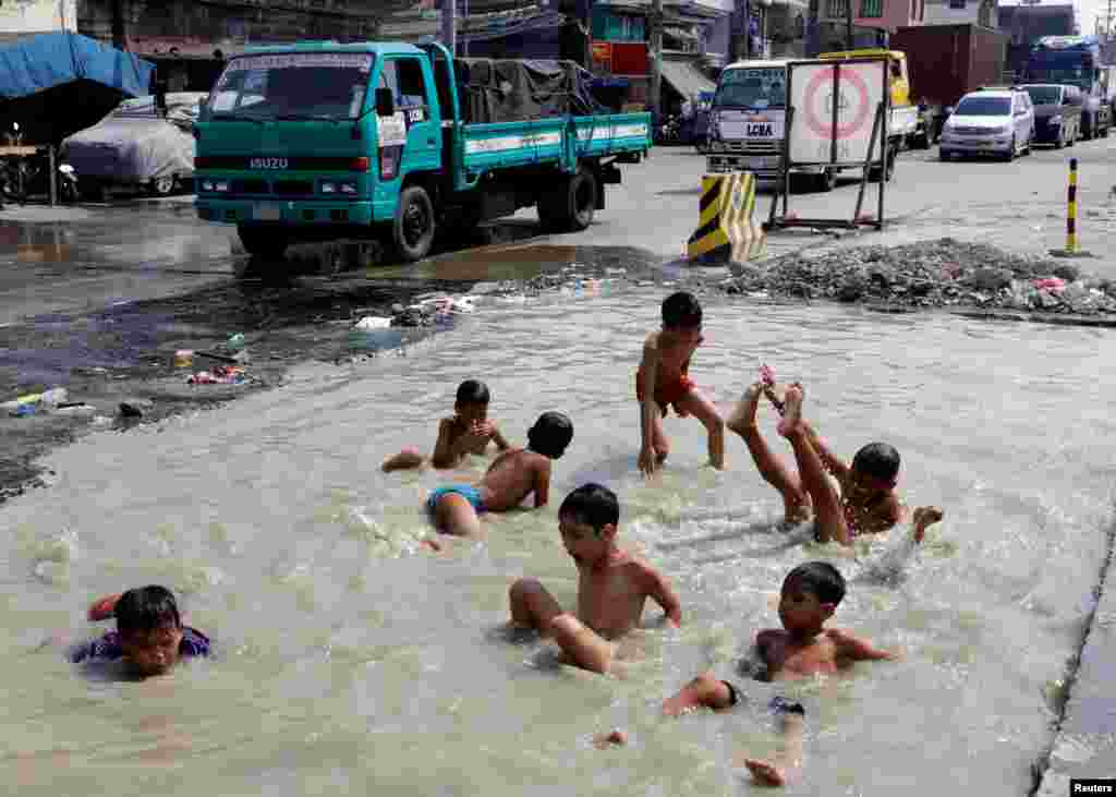 Young boys swim in a flooded road under repair in Tondo district, metro Manila, Philippines.
