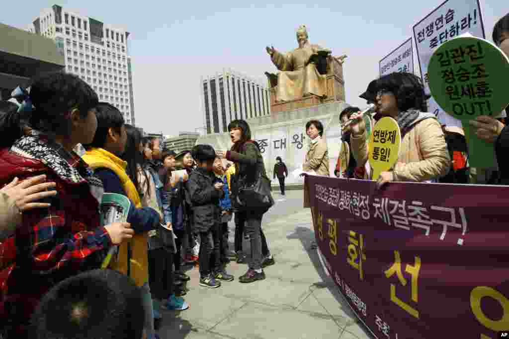 2013年4月8日一群韩国家庭主妇在靠近首尔美国驻韩国大使馆附近谴责美韩两国举行的一年一度的军事演习,一名小学教师命令正在观看这场景的学生们离开现场。