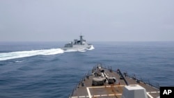 资料照片：美国海军公布的照片显示，美军导弹驱逐舰“钟云号”（USS Chung-Hoon）2023年6月3日在台湾海峡国际海域穿行时，一艘中国军舰在前方危险行驶。
