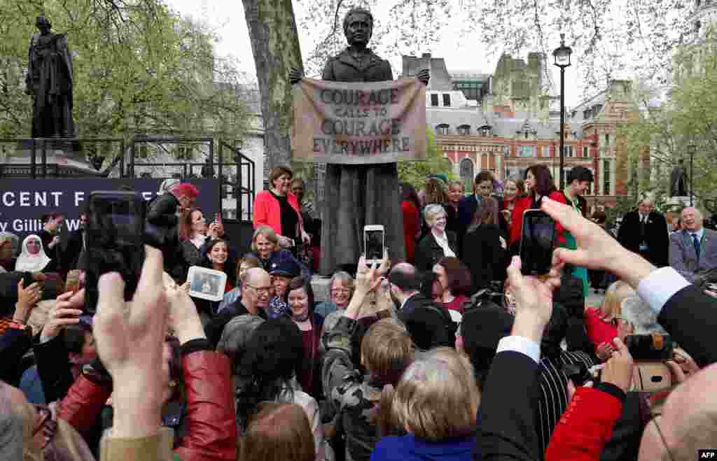 People pose for photographs with a statue of suffragist and women's rights campaigner Millicent Fawcett by British artist Gillian Wearing after it was unveiled in Parliament Square in London.