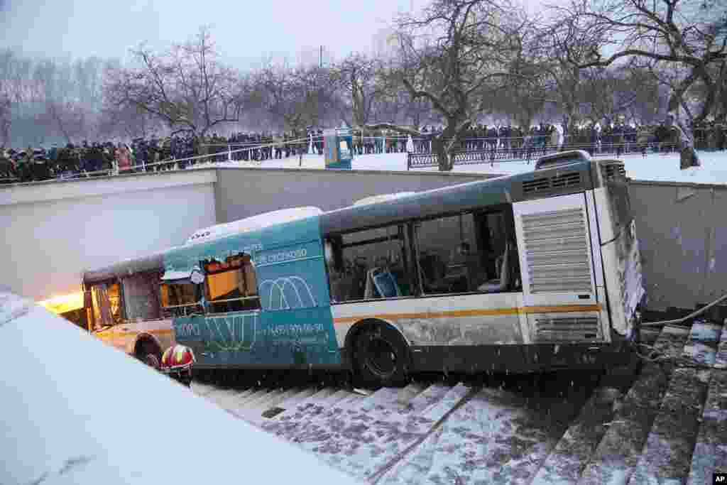 Pedestrians stand around the scene of a bus crash in Moscow, Russia. Several people were killed and more than a dozen injured when a bus careened off a road and onto steps leading into an underground passageway, authorities said.