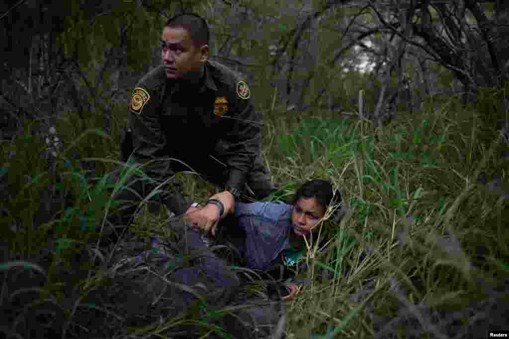 A border patrol agent apprehends a woman and a man after they were caught illegally crossing into the U.S. border from Mexico near McAllen, Texas,, May 2, 2018.