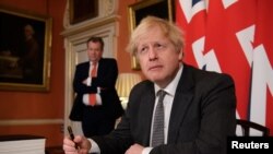 资料照片：英国首相约翰逊在首相官邸签署文件（2020年12月30日）