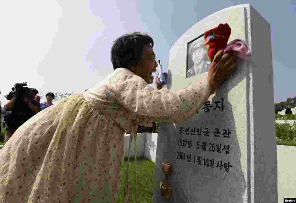 一名朝鲜女子对着墓碑哭泣,哀悼她在朝鲜战争期间死亡的父亲。
