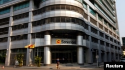 FILE - A woman walks past the head office of Angola's state oil company Sonangol in the capital Luanda, Angola, Aug. 26, 2012. 
