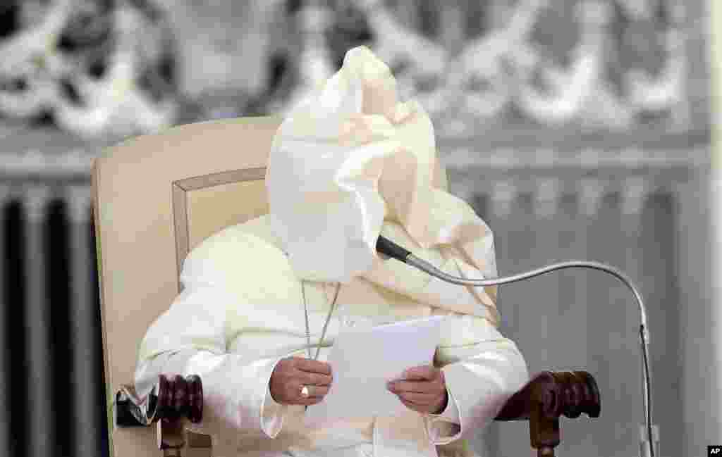 A gust of wind blows Pope Francis' mantle as he reads his message during his weekly general audience in St. Peter's Square at the Vatican.