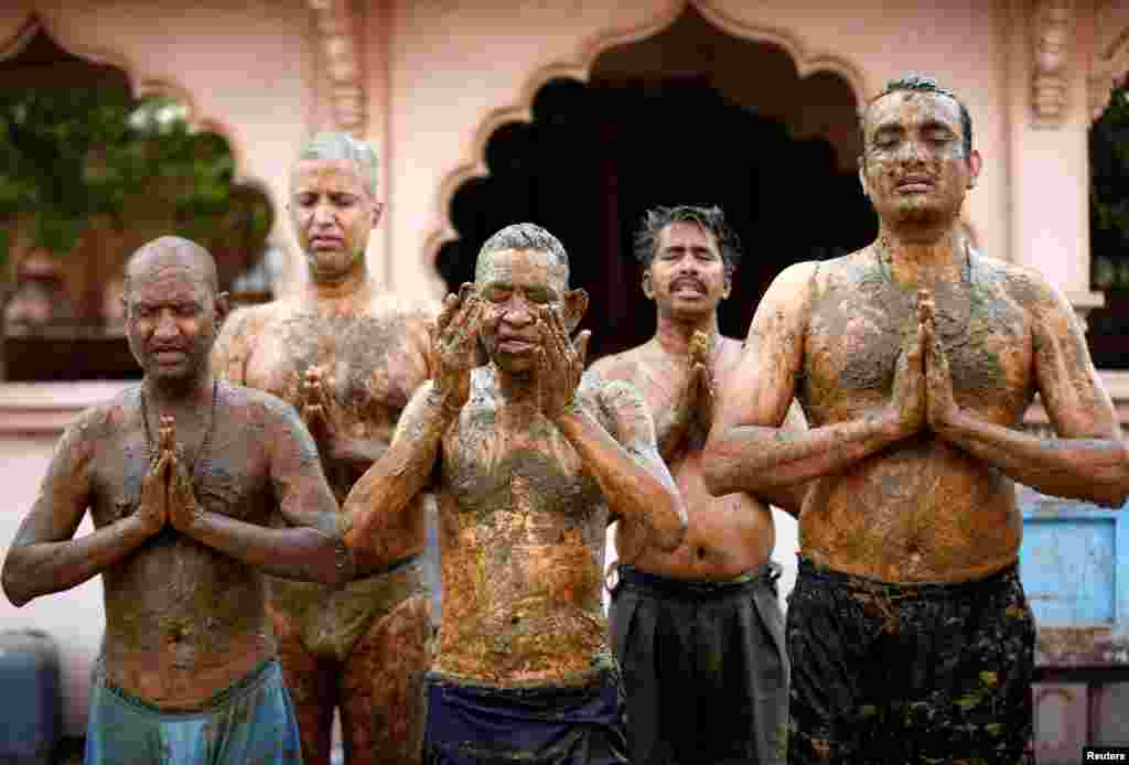 People pray after applying cow dung on their bodies during "cow dung therapy", believing it will boost their immunity to defend against the COVID-19 at a cow shelter on the outskirts of Ahmedabad, India.