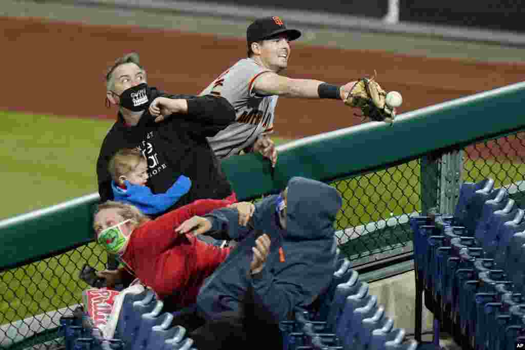 San Francisco Giants right fielder Mike Yastrzemski cannot reach a pop foul ball by Philadelphia Phillies' Rhys Hoskins during the ninth inning of a baseball game, April 20, 2021, in Philadelphia, Pennsylvania.