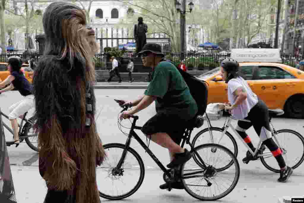 A person dressed as the Chewbacca character stands on a sidewalk as bicycle commuters pass by on 6th Avenue during a promotion for the upcoming film "Solo: A Star Wars Story" in Manhattan, New York City.
