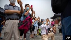7月18日星期六，戴口罩的学生父母在北京天坛公园给学生照集体照。