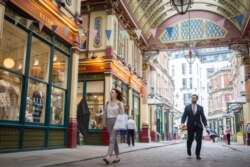 People walks past shops and restaurants at Leadenhall Market in the City of London on July 27, 2021.
